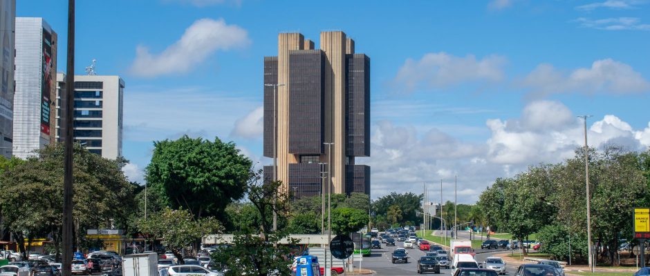 Vista externa do edifício do Banco Central do Brasil em Brasília, sob um céu colorido.