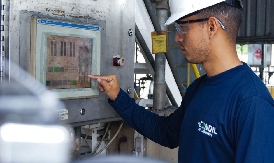 Profissional opera um painel de controle em uma instalação industrial.