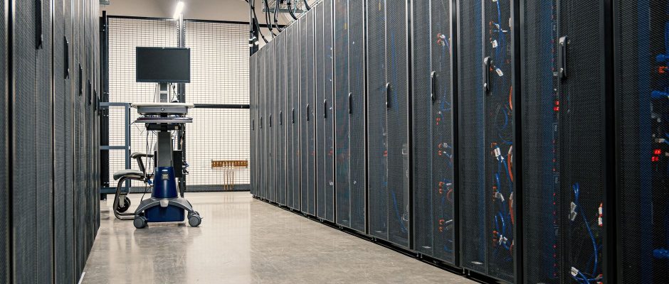 Armários metálicos com servidores, equipamentos de rede e cabos em um data center moderno.