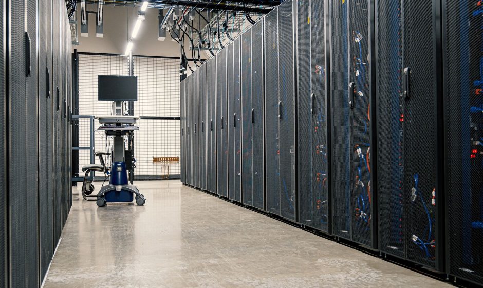 Armários metálicos com servidores, equipamentos de rede e cabos em um data center moderno.