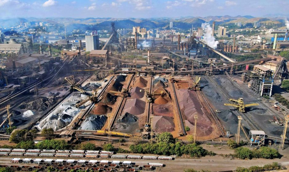 Vista ampla de uma instalação industrial de mineração, com máquinas e pilhas de rejeitos.