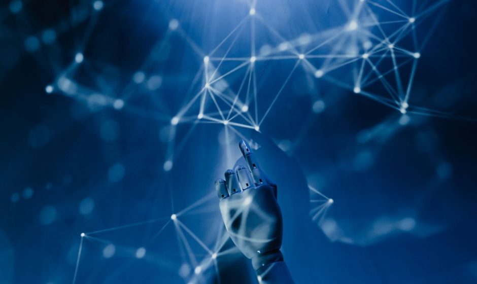 Mão robótica diante de uma rede digital azul, representando tecnologia e conectividade.