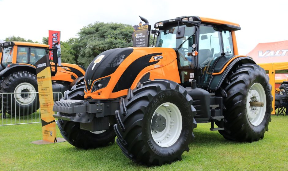 Trator agrícola Valtra exposto em evento ao ar livre, diante de uma área verde.