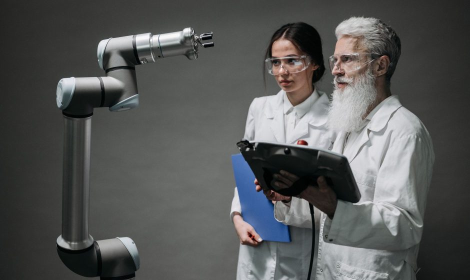 Pesquisadores examinam um braço robótico em um laboratório de tecnologia.